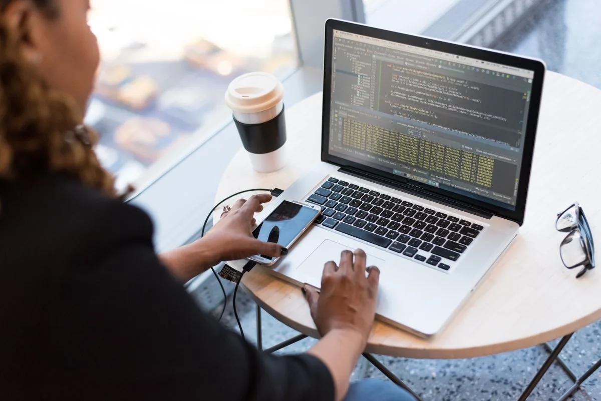 Developer creating a responsive website using a laptop and mobile phone